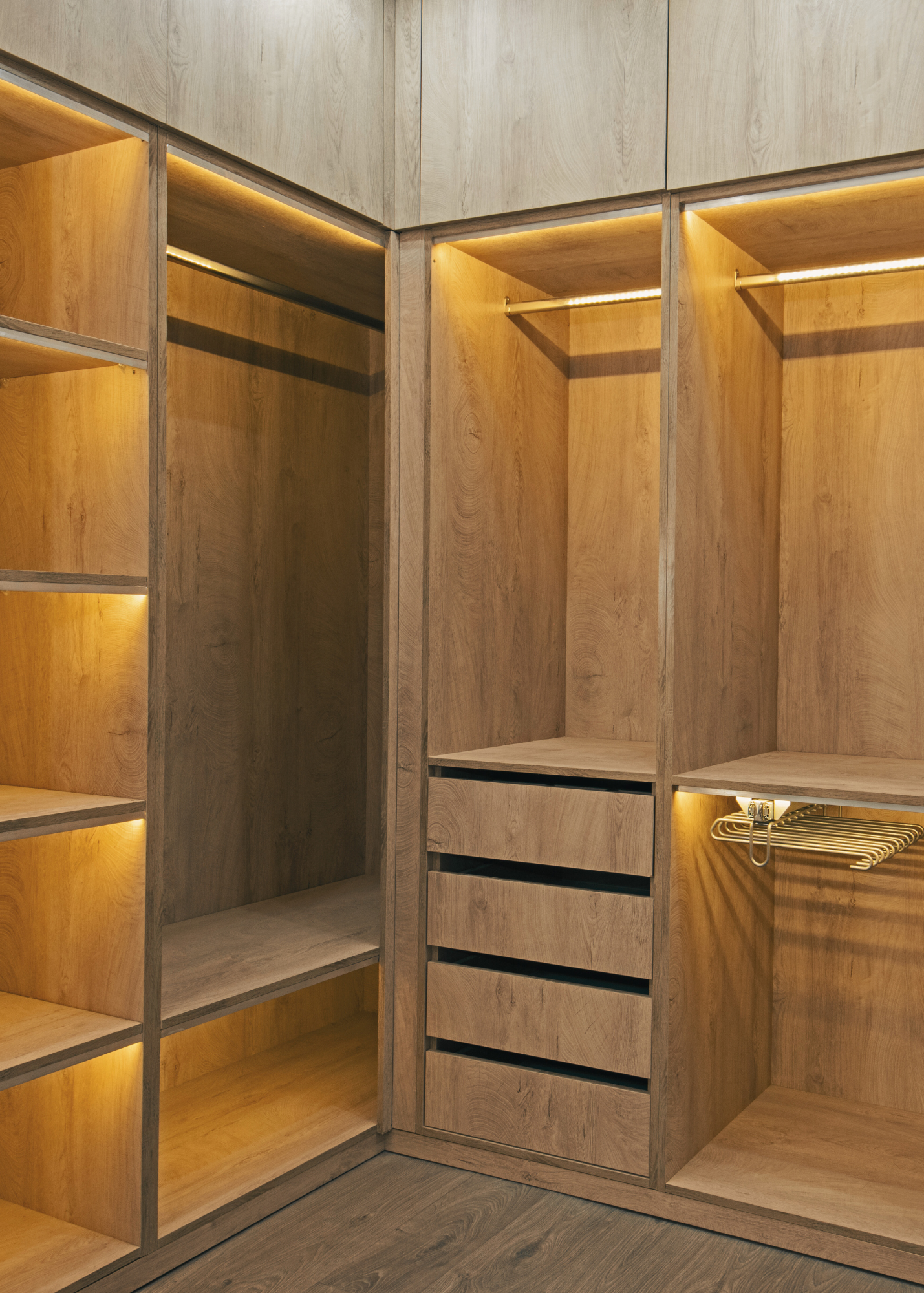 Custom built-in wood closet with drawers, shelving, and warm accent lighting